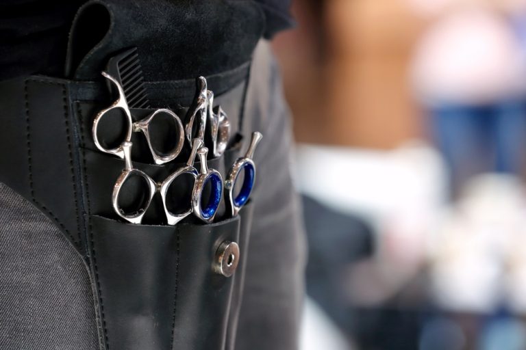 cosmetologist apron holding various scissors and combs
