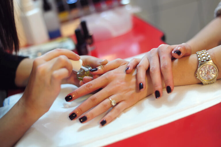 Nail technician practicing manicure techniques at Austin Kade Academy.