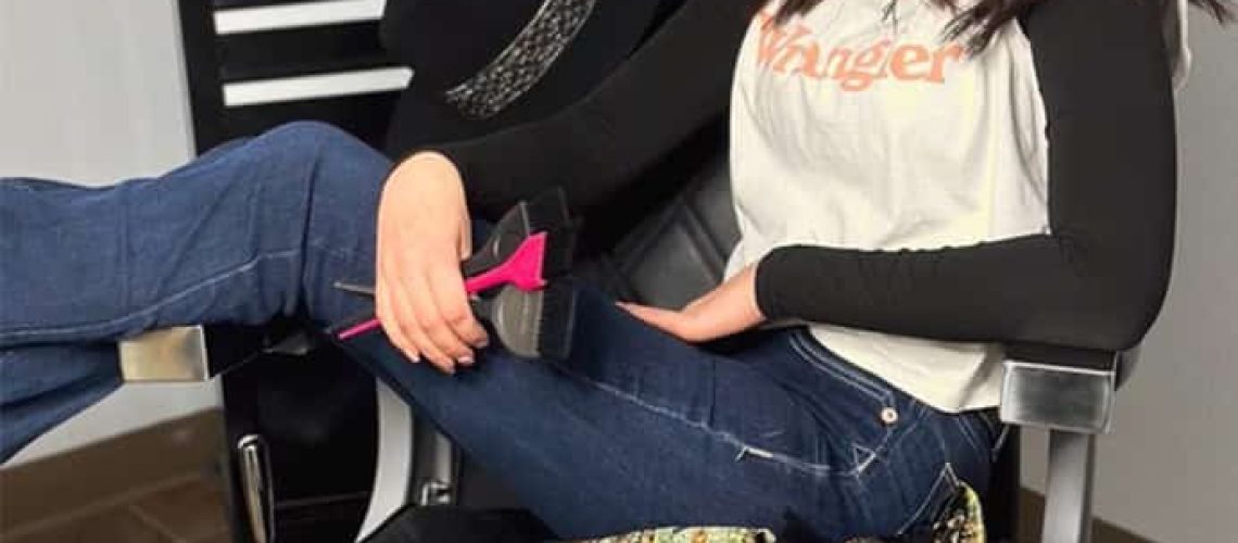 Cosmetology student posing in a salon chair at a cosmetology school in Idaho Falls.
