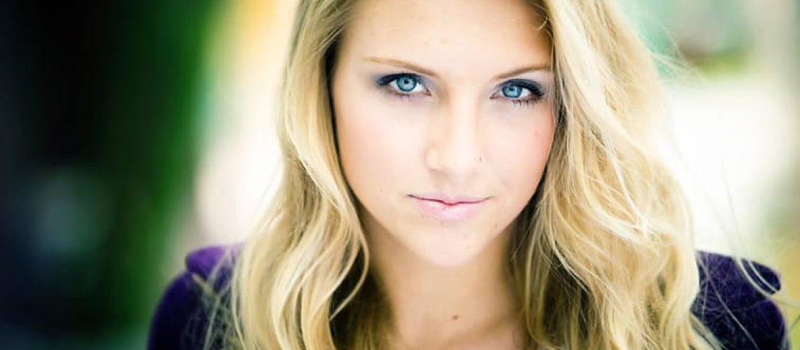 Young woman with blonde hair and blue eyes, representing confidence and professionalism in beauty