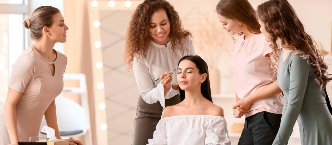 Students practicing makeup application in a cosmetology classroom.