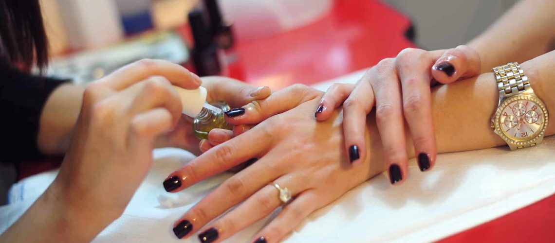 Nail technician practicing manicure techniques at Austin Kade Academy.