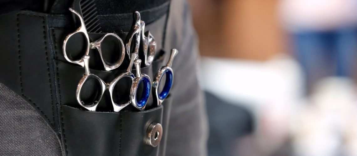 cosmetologist apron holding various scissors and combs