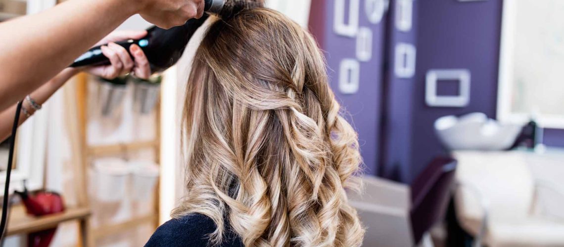 Beautiful hairstyle of young adult woman after dyeing hair and making highlights in hair salon.