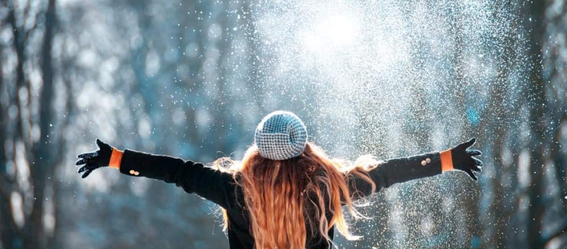 Performer with long hair and a microphone in a snowy outdoor setting, celebrating success