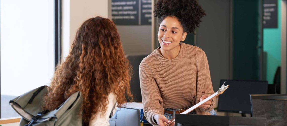 Young woman checks in at front desk, reception, hotel, college library admission